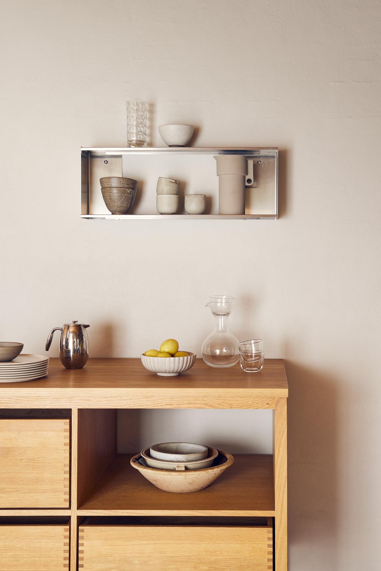 Form & Refine Taper Wandregal klein aus Edelstahl mit Geschirr und Dekoration an der Wand.