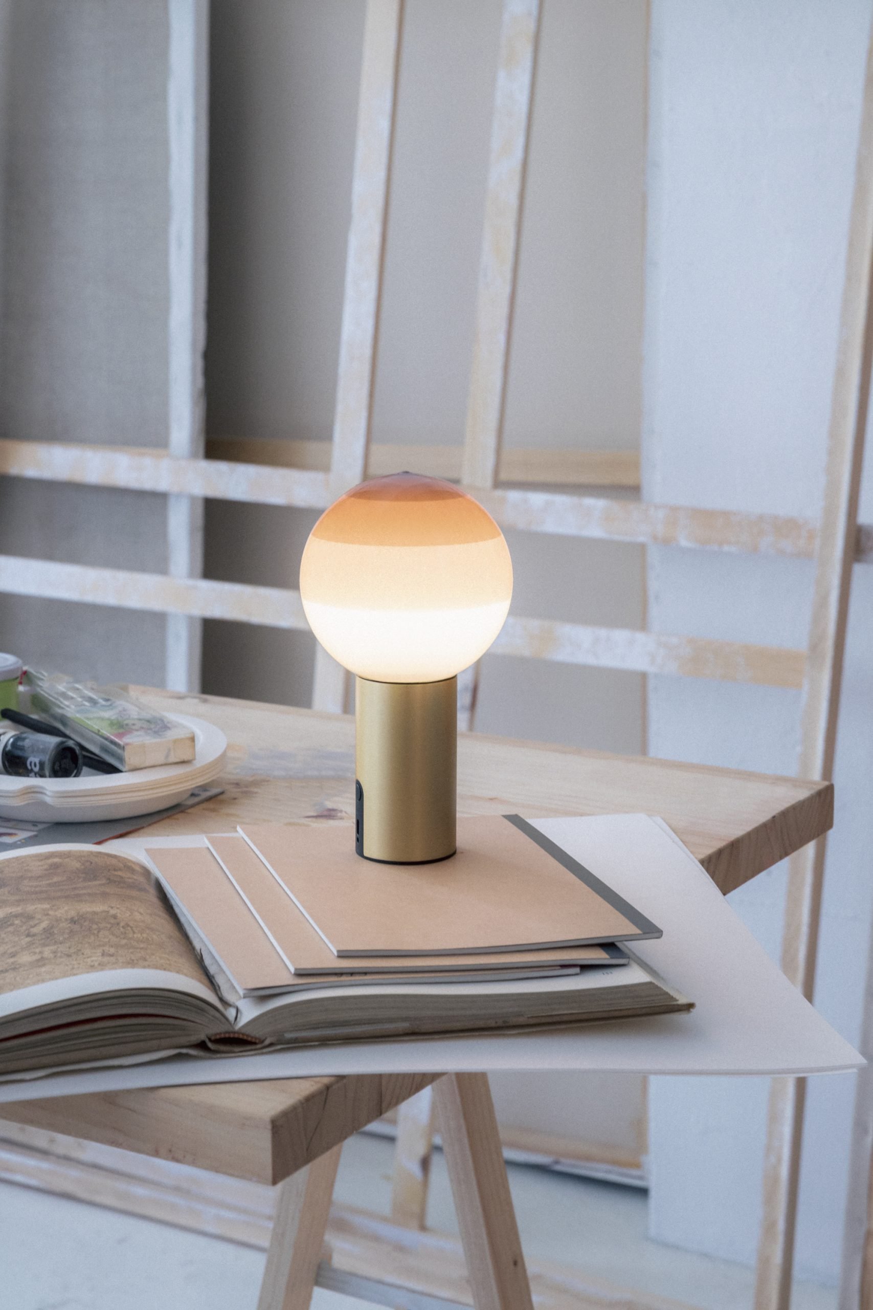 Nahaufnahme der Marset Dipping Light S LED Tischleuchte mit Farbverlauf auf einem Tisch.