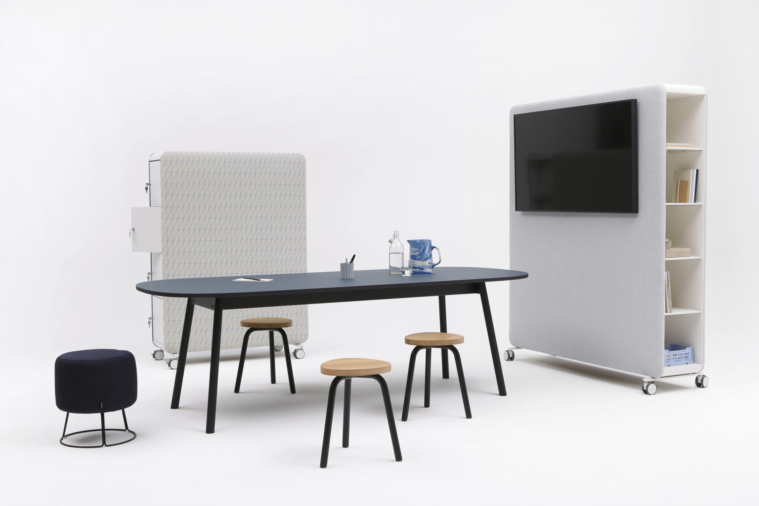 Cascando Pillow Space Akustik-Raumteiler mit Tisch, Stühlen und einem Raumteiler mit integriertem Bildschirm für moderne Büroräume.
