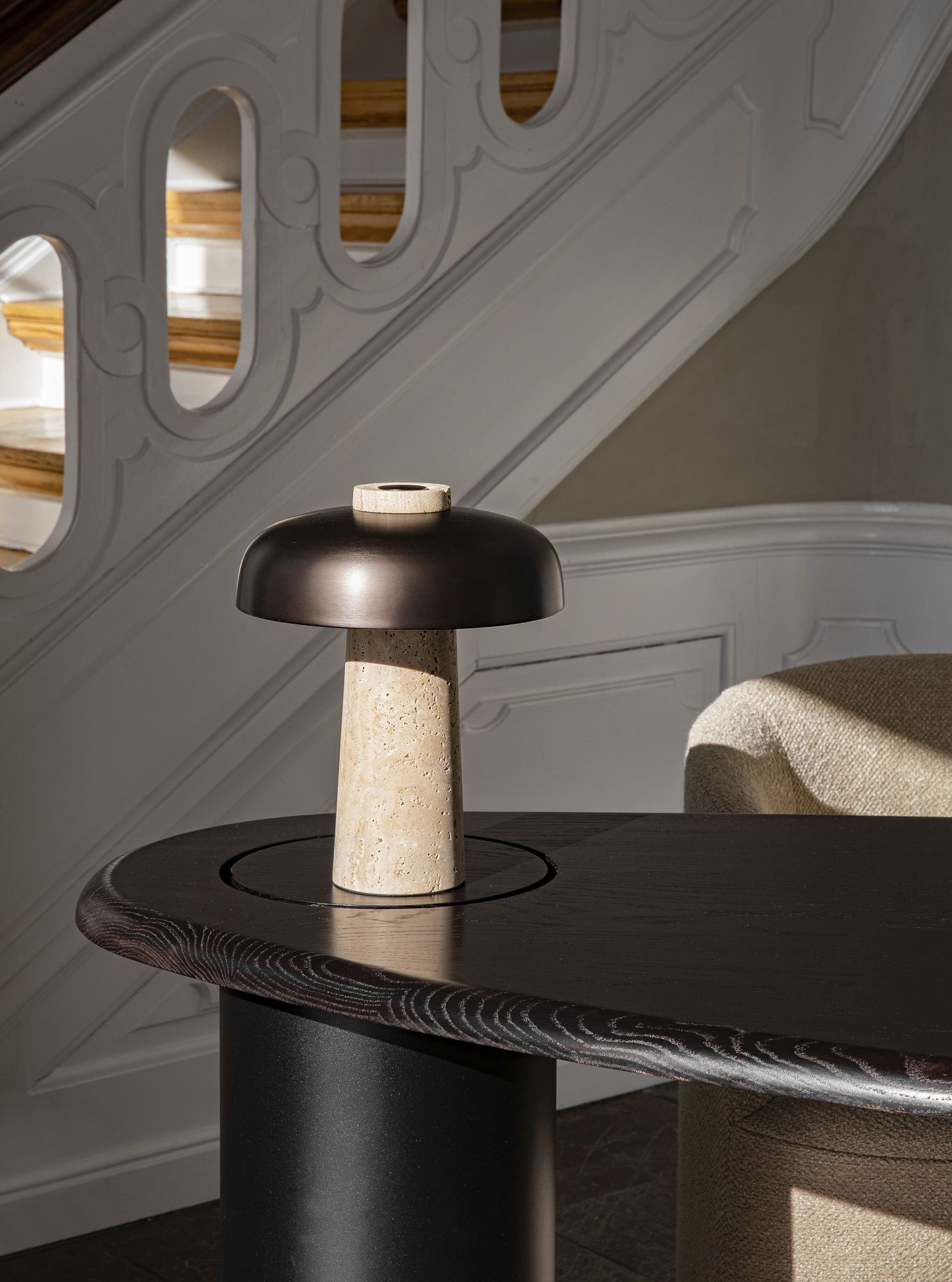Nahaufnahme des Audo Copenhagen Eclipse Desk Schreibtischs mit stilvoller Tischleuchte und Treppenhaus im Hintergrund.