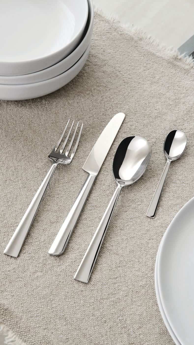 Nahaufnahme der Asta Besteckgarnitur von Alessi, bestehend aus Messer, Gabel, Esslöffel und Teelöffel.