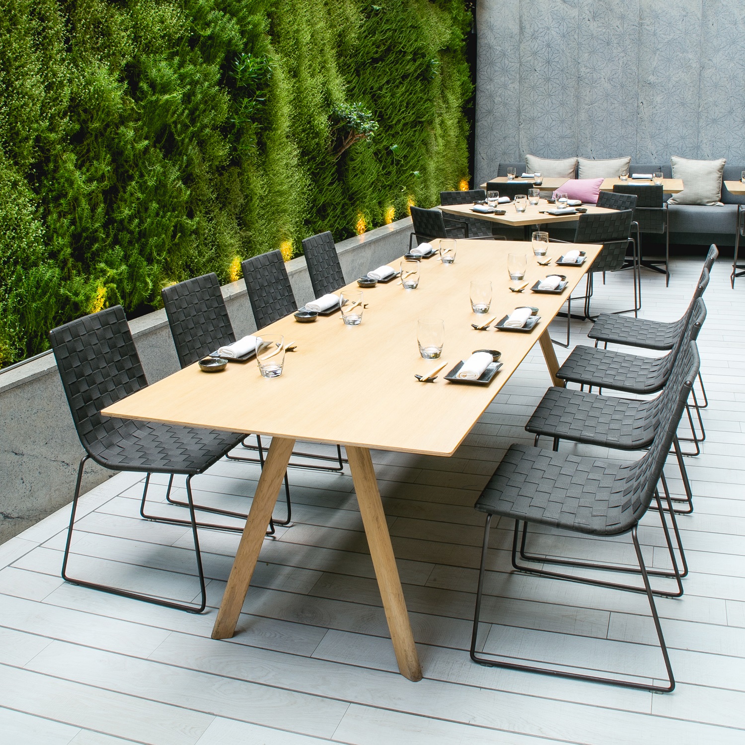 Andreu World Trenza Stuhl SI0700, stapelbarer Outdoor-Stuhl mit geflochtener Sitzfläche und schwarzem Metallgestell.