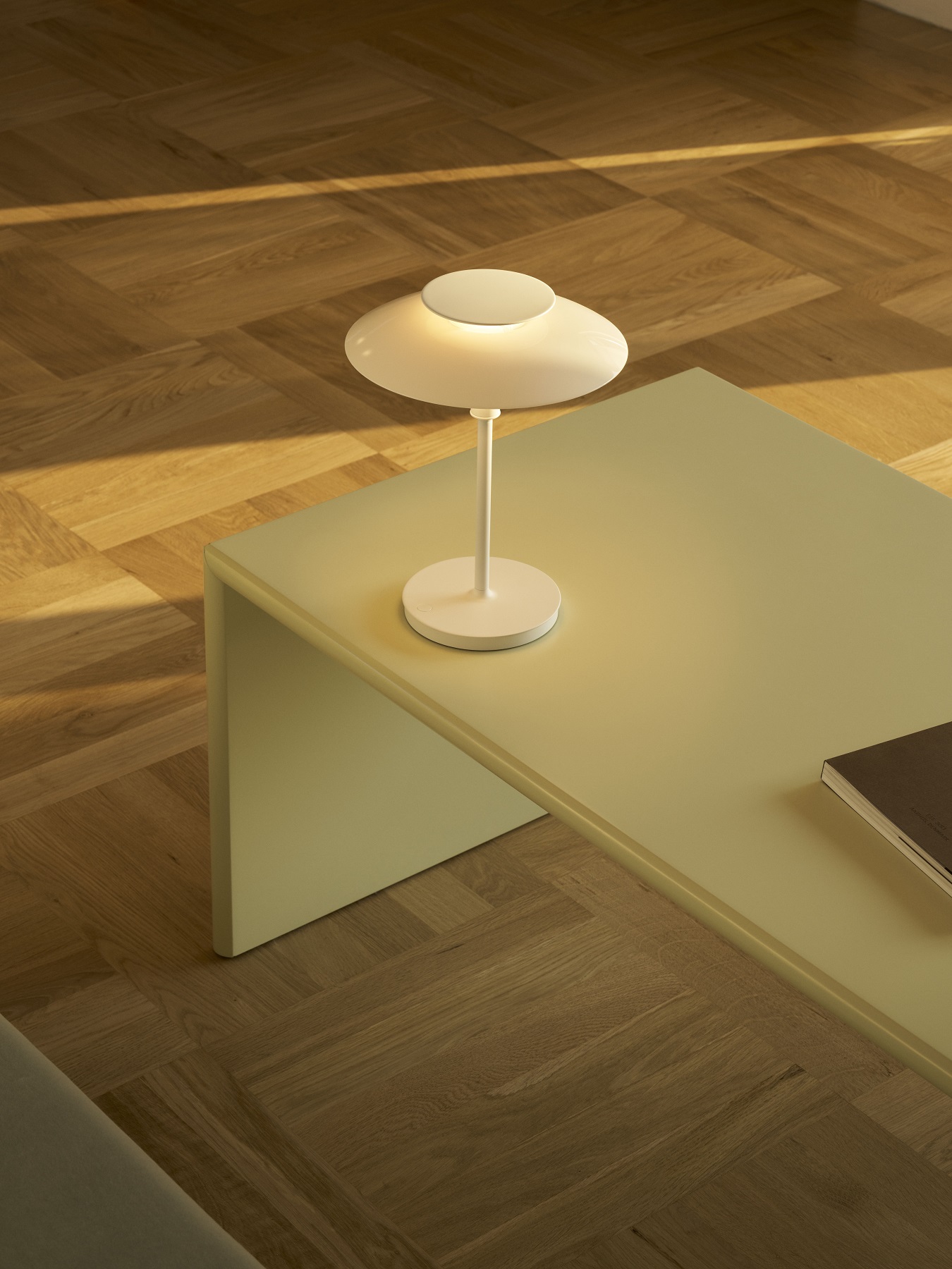 Weiße Louis Poulsen PH 80 Tischleuchte auf einem Tisch, warmes Licht, modernes Design.