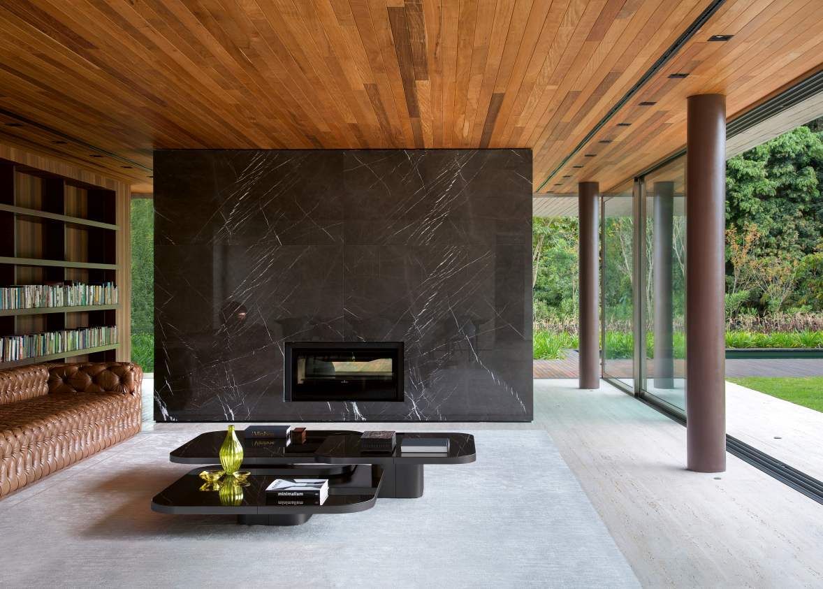 Moderner Wohnraum mit ClassiCon Bow Coffee Table No. 3, schwarzer Couchtisch mit Glasplatte vor Marmorwand.