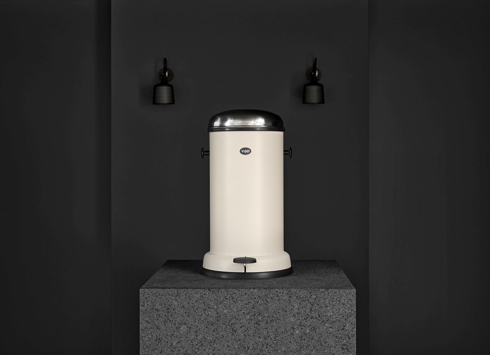 Beige Vipp Treteimer, 8 Liter, aus Stahl und mit Pedal auf einem grauen Sockel.