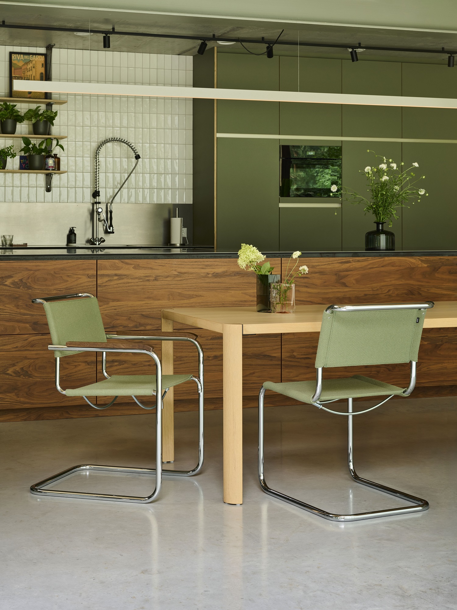 Zwei grüne Thonet S 34 Freischwinger Stühle aus Stahlrohr an einem Holztisch in moderner Küche.