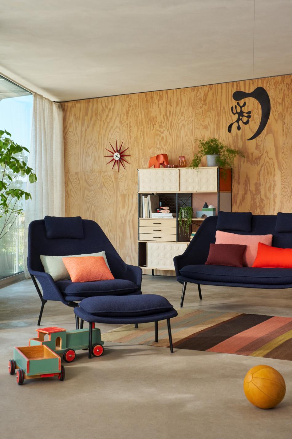 Vitra Slow Chair Sessel mit Ottoman in blauem Stoffbezug in modernem Wohnzimmer.