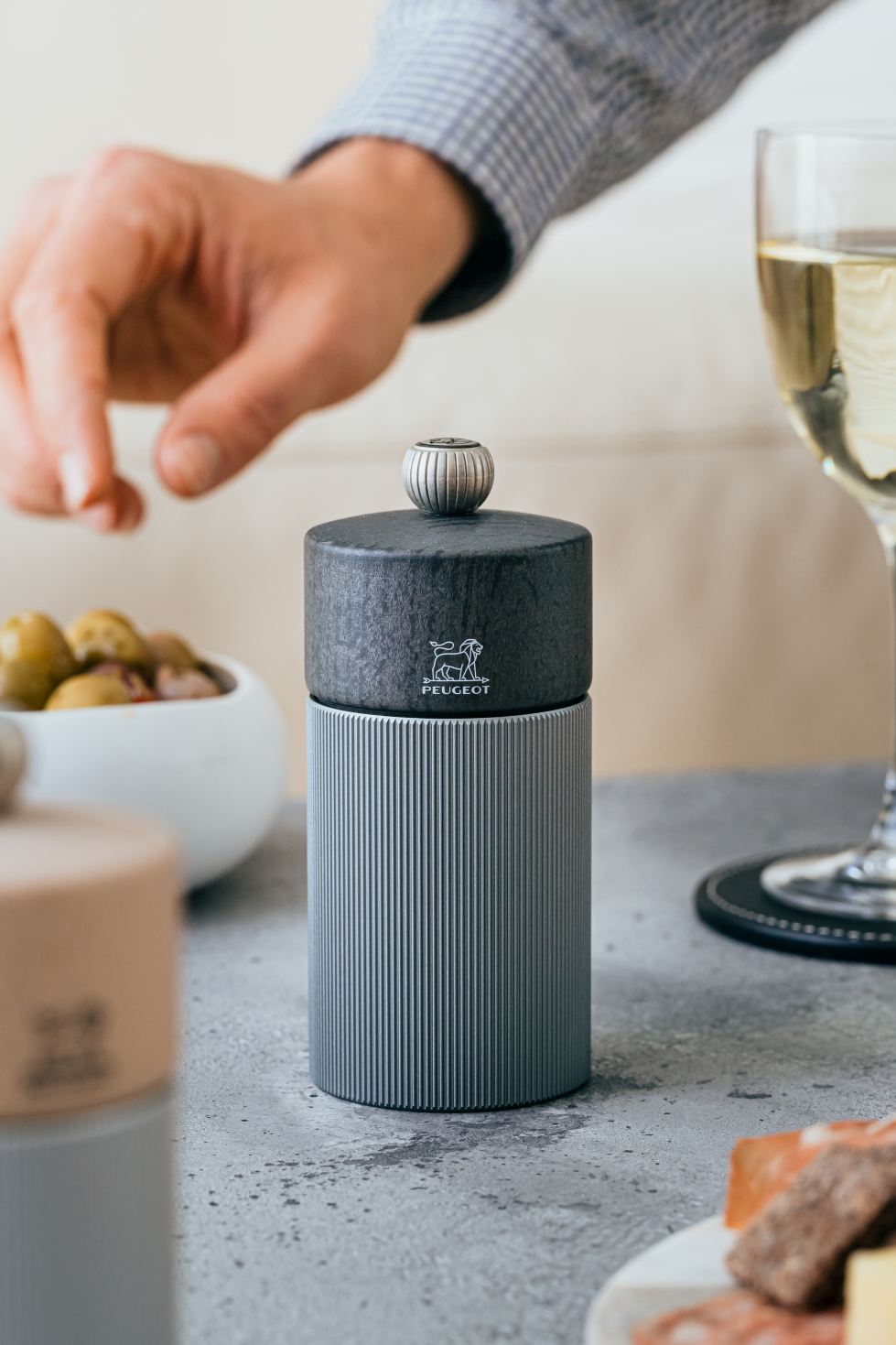 Nahaufnahme der Peugeot Line Pfeffermühle H 12 cm in Graphit & Carbon auf gedecktem Tisch.