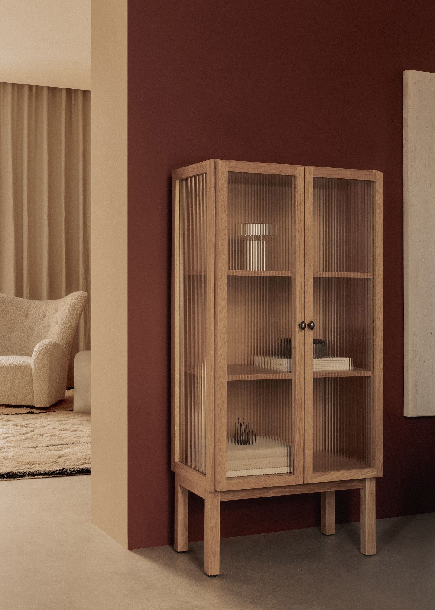 Audo Copenhagen Curiosity Cabinet Low aus Eiche mit geriffeltem Glas und schwarzen Griffen.