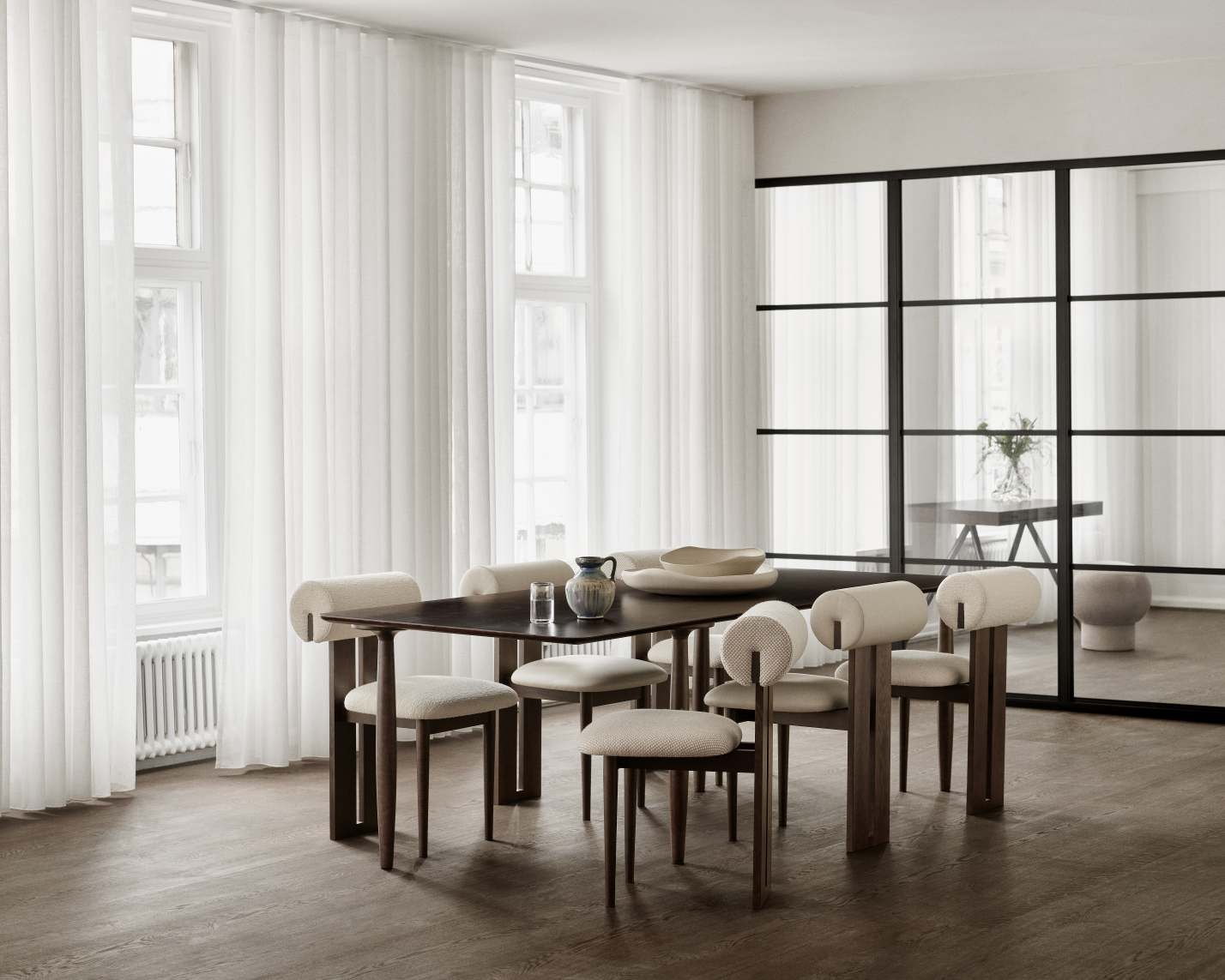 Esszimmer mit dunklem Holztisch und sechs Hippo Stühlen von NORR11 mit beigen Polstern.