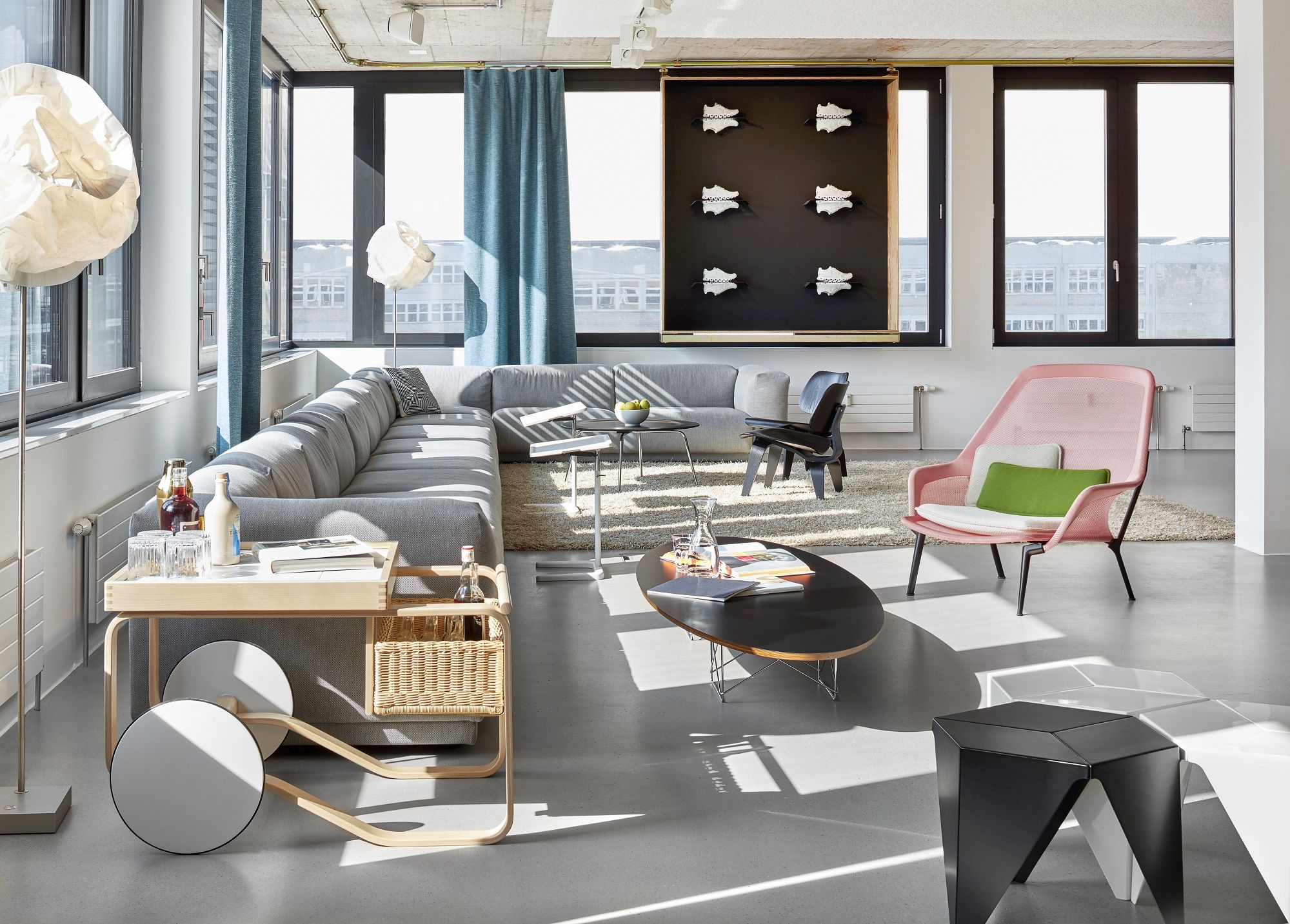 Heller Wohnraum mit Vitra Slow Chair Sessel in Rosa, grauer Couch und Designermöbeln für ein modernes Ambiente.