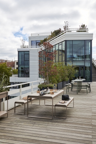 Bolder 3-Sitzer-Tisch mit Sitzflächen von Fermob, ideal für stilvolle Outdoor-Bereiche auf einer Dachterrasse.