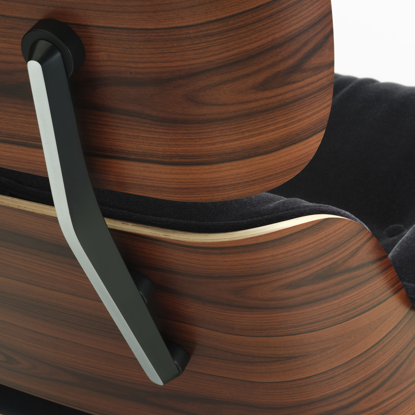 Detailaufnahme Eames Lounge Chair von Vitra: Walnussfurnier, schwarze Polsterung und Armlehne. Hochwertiger Designklassiker.