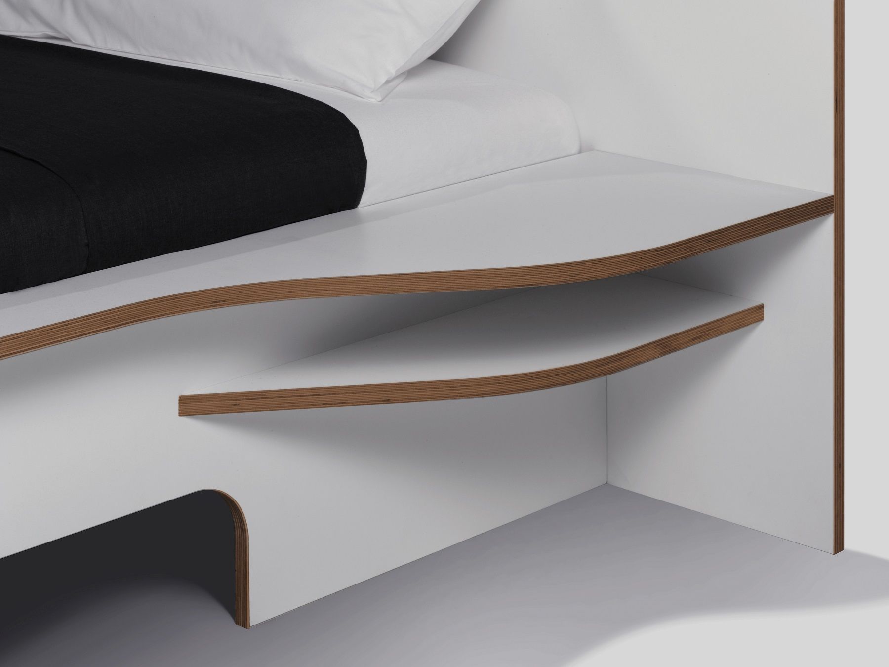 Detailaufnahme vom weißen Plane Doppelbett von Müller Möbelwerkstätten mit Ablagefächern aus Holz.