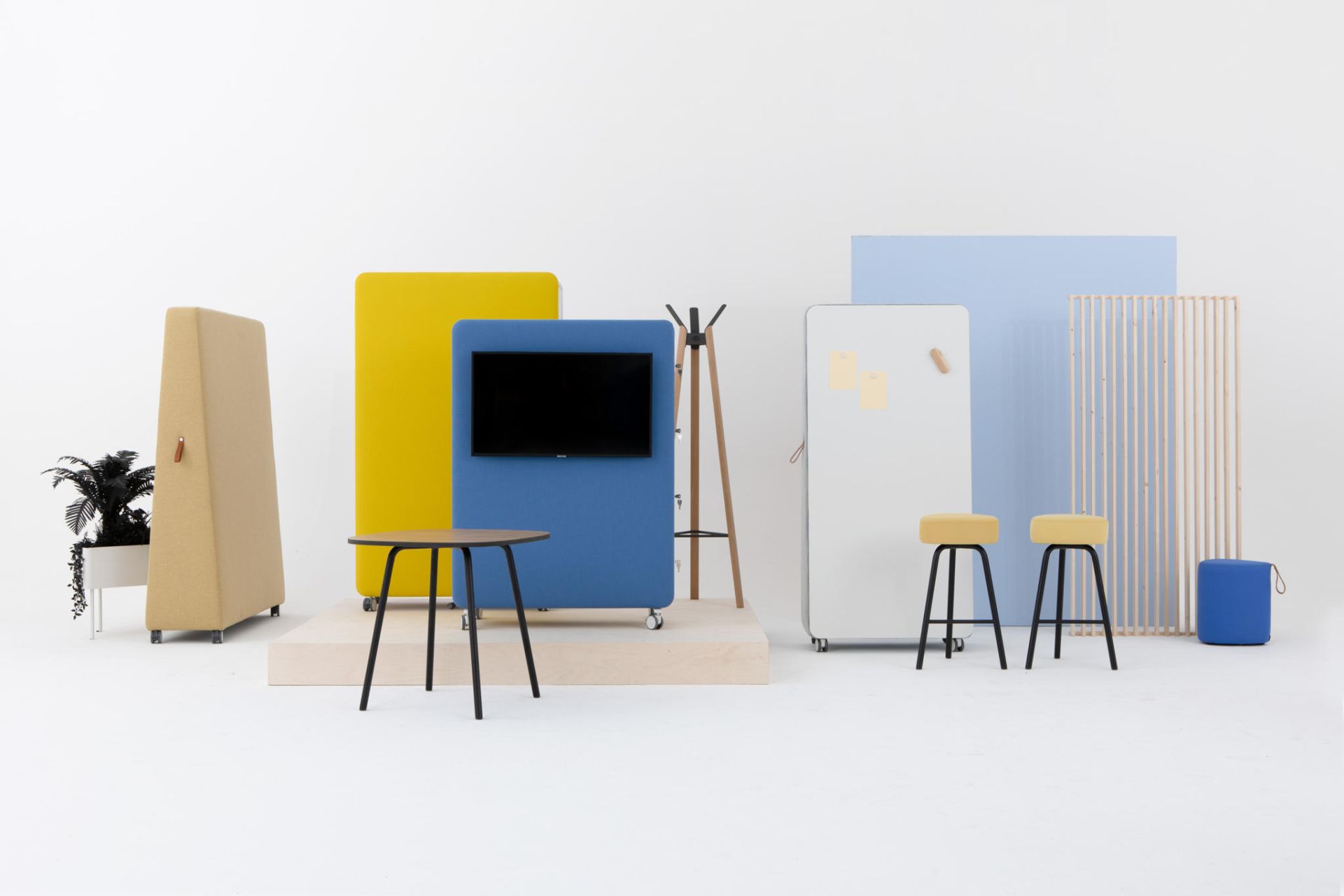 Cascando Pillow Space Akustik-Raumteiler in Gelb, Blau und Beige mit Tisch, Hocker und Garderobe.
