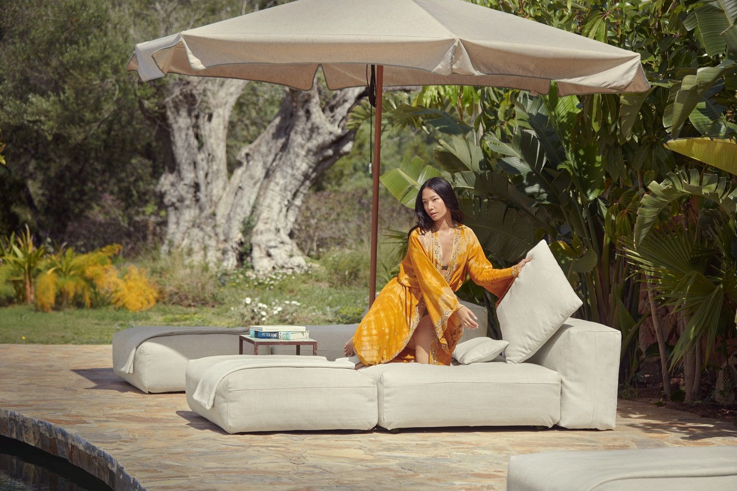 Frau entspannt auf Vetsak Sun Lounger Outdoor Liege unter Sonnenschirm im Garten. Luxuriöses 2-Sitzer Sofa Set für den Außenbereich.