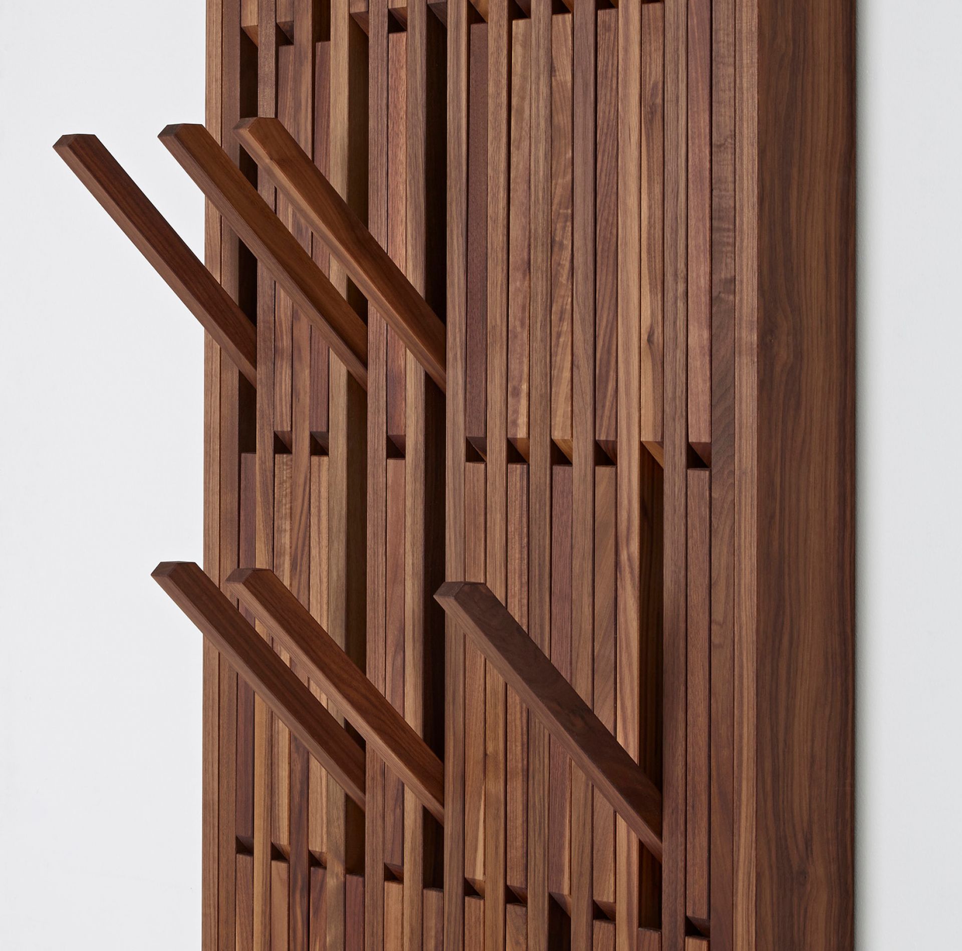 Detailaufnahme der Piano Wandgarderobe aus geöltem Walnussholz mit ausklappbaren Haken.