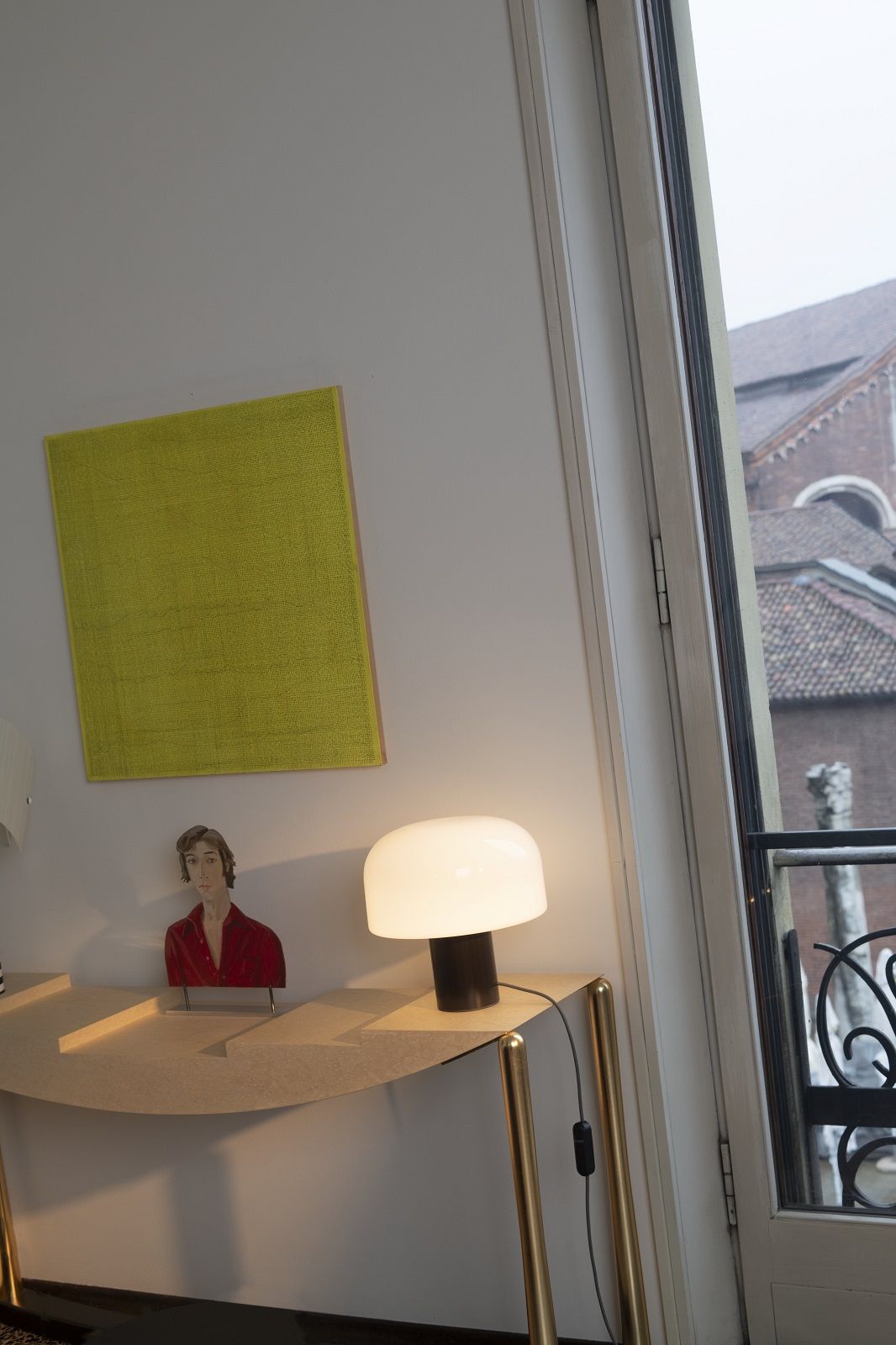Nahaufnahme der Bellhop Glass T Tischleuchte von Flos auf einem goldenen Tisch.