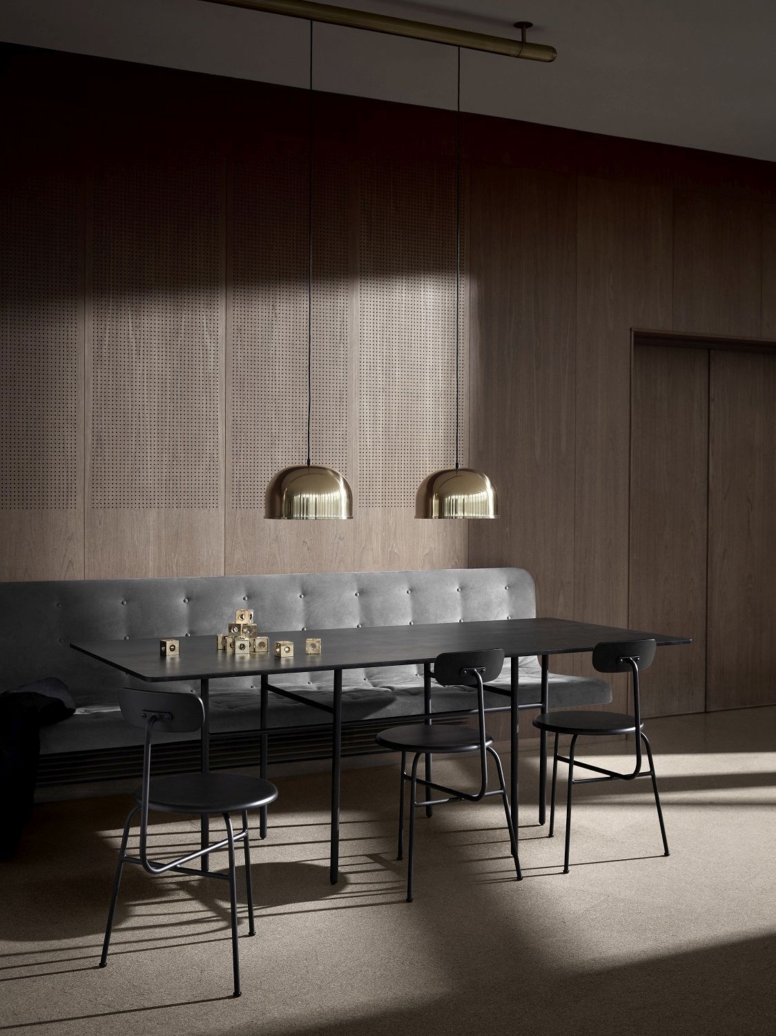 Esszimmer mit schwarzem Tisch, grauer Bank und vier schwarzen Afteroom Dining Chairs von Audo Copenhagen.