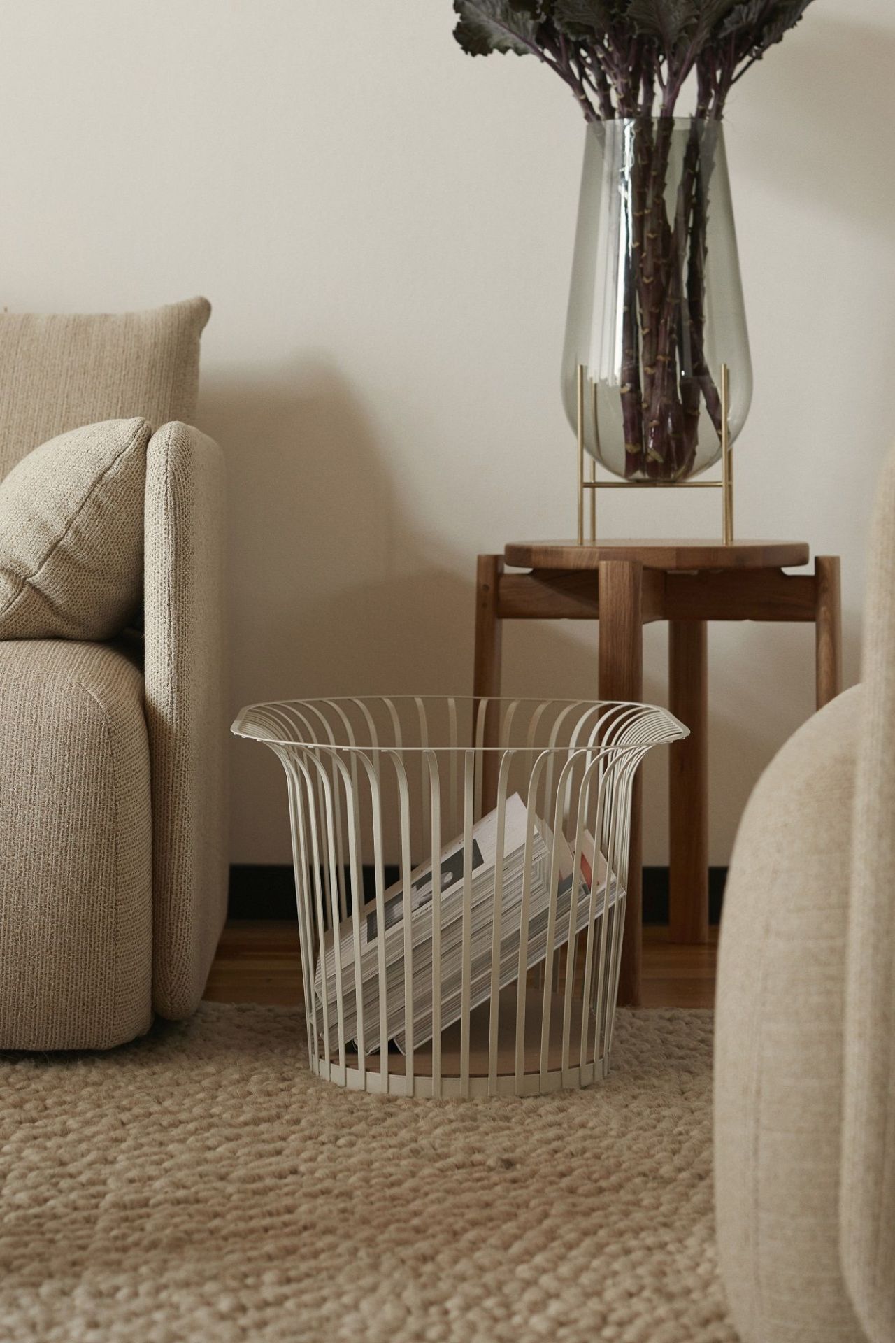 Detailaufnahme eines weißen Audo Copenhagen Passage Stool Hockers aus Metall, der als Zeitschriftenständer im Wohnzimmer dient.