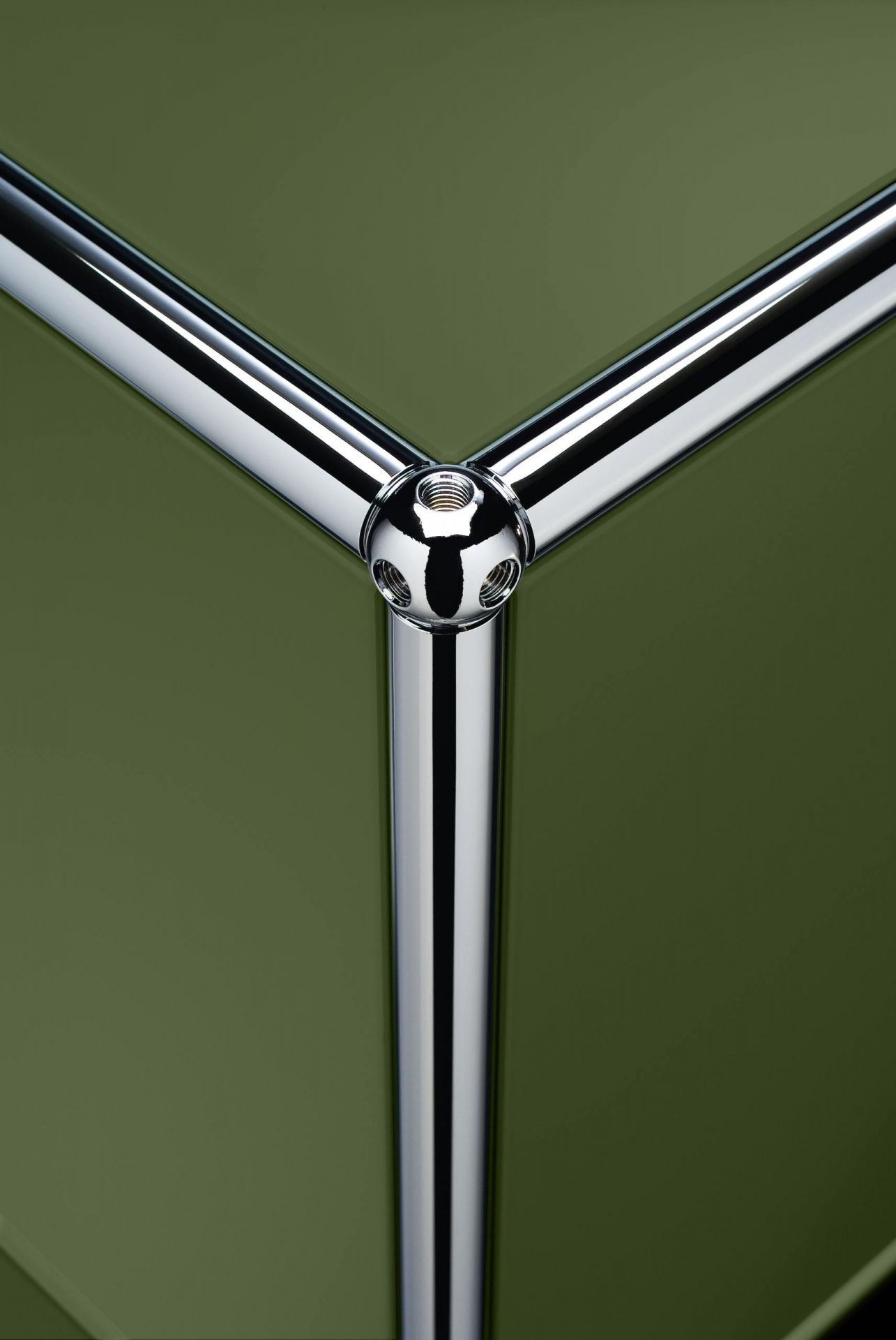 Detailaufnahme USM Haller Sideboard in Olivgrün: Chrom-Verbinder vor grüner Oberfläche.