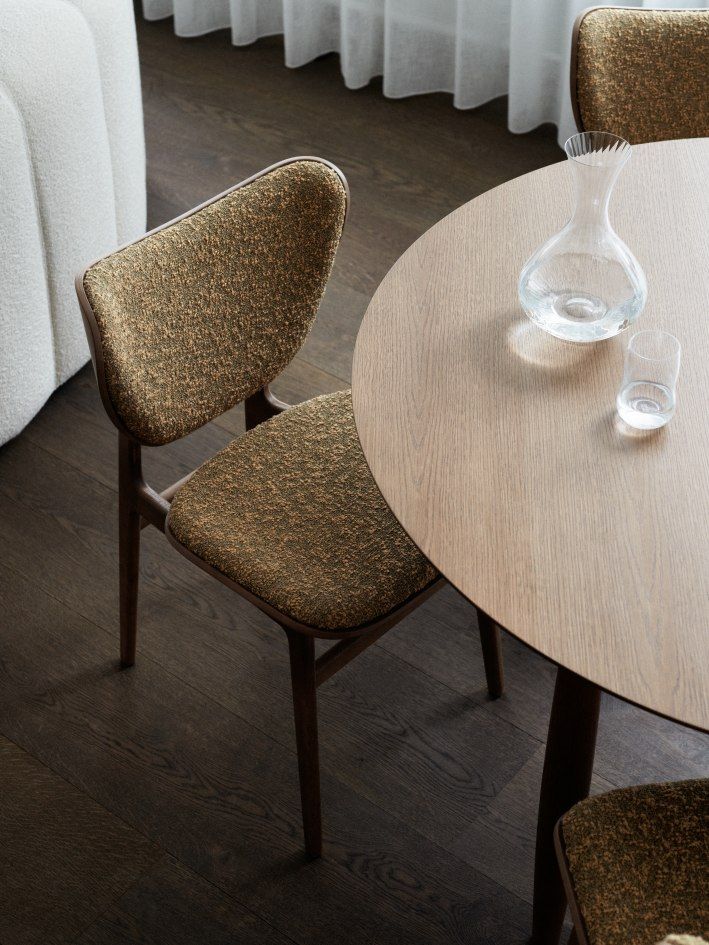 Nahaufnahme eines NORR11 Elephant Dining Chair Stuhls mit braunem Stoffbezug am Esstisch.