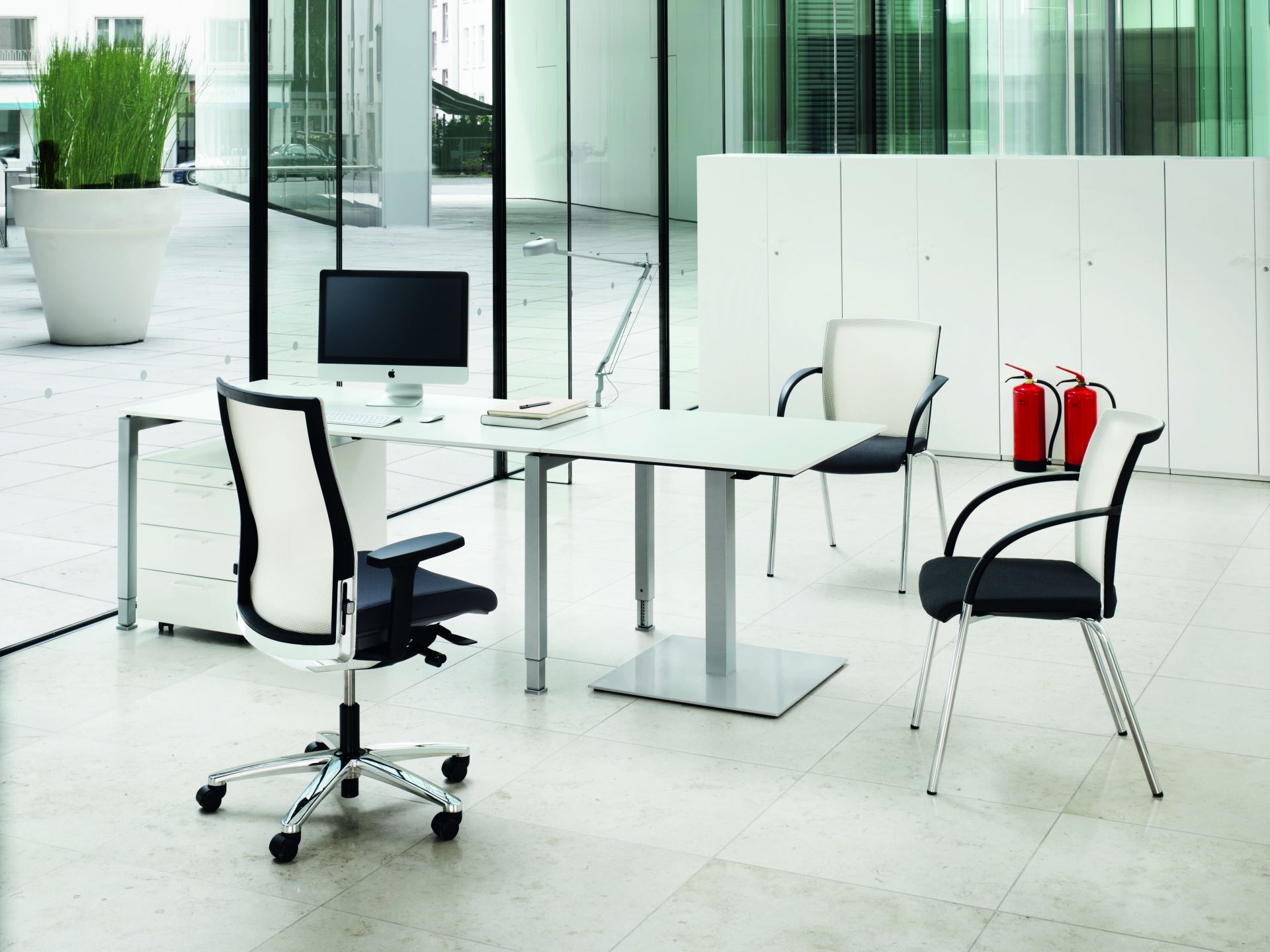 König+Neurath Schreibtisch höhenverstellbar: Moderner Bürotisch mit Bürostuhl und Besucherstühlen in hellem Büro.