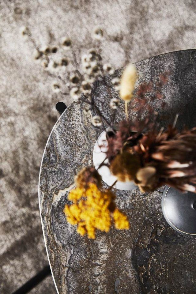 Nahaufnahme des La Terra Couchtischs von Woud in Grau Melange mit dekorativen Trockenblumen.