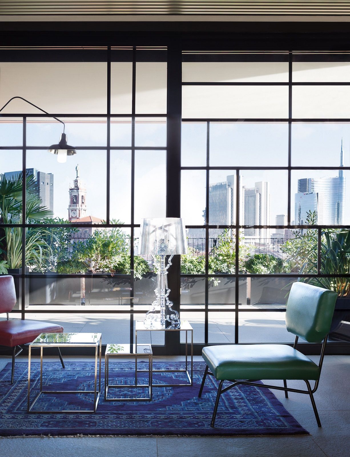 Glasklare Bourgie Tischleuchte von Kartell auf einem Beistelltisch vor einem Fenster mit Stadtblick.
