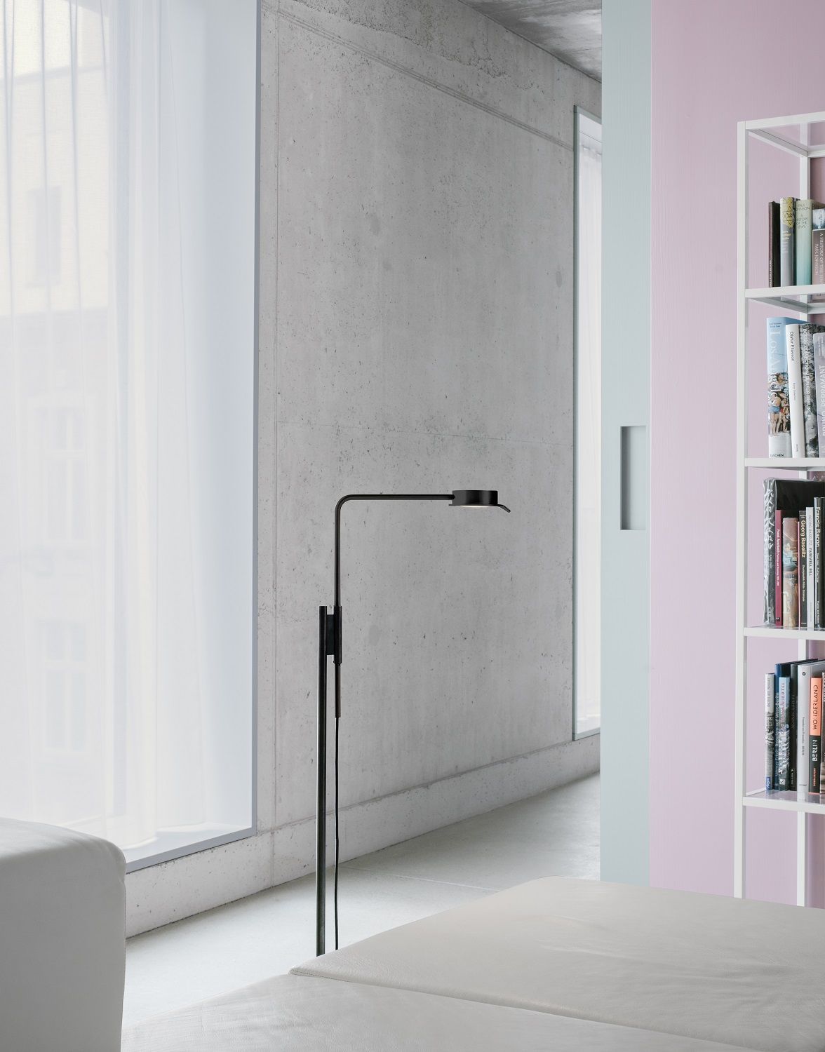 Schwarze w102 F Chipperfield Stehleuchte von wästberg im modernen Wohnzimmer mit Betonwand und Bücherregal.