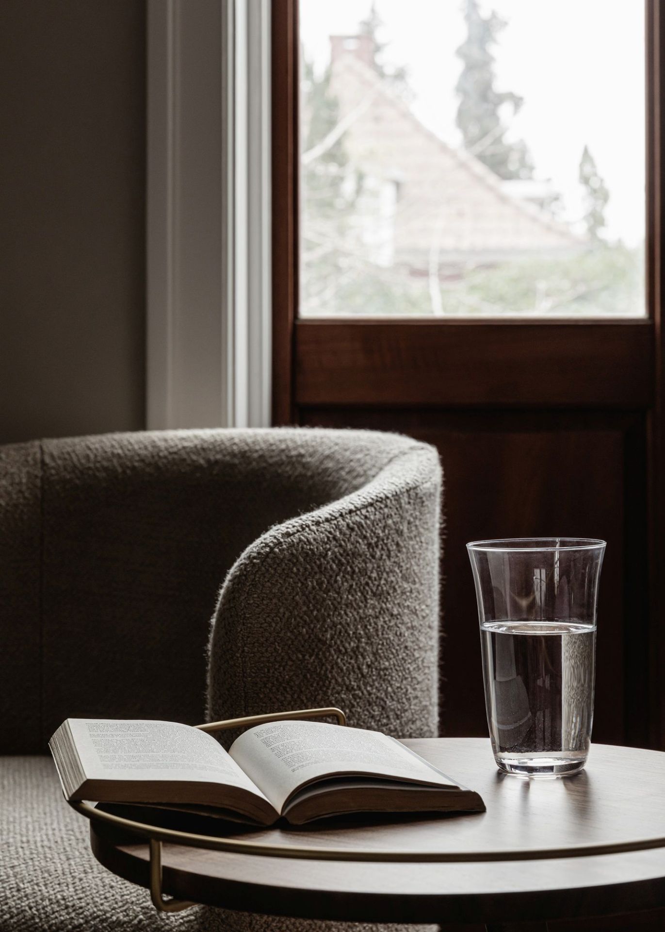 Tearoom Club Chair Sessel von Audo Copenhagen mit Buch und Wasserglas auf Beistelltisch.