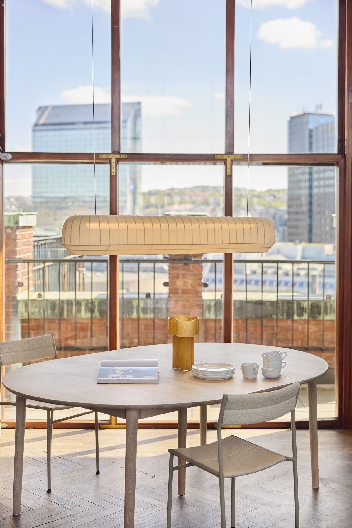 Nahaufnahme des Northern Expand Dining Table Circular Ausziehtisch Esstisch mit Geschirr und Stühlen in hellem Raum.