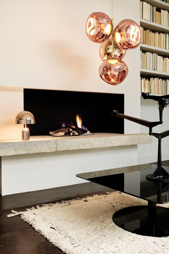 Modernes Wohnzimmer mit Tom Dixon Spin Kerzenständer, Kamin, Lampe und Bücherregal für stilvolle Inneneinrichtung.