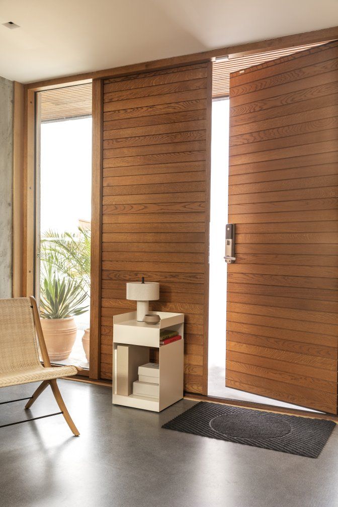 Dunkelgraue Møne Fußmatte von Heymat vor einer offenen Holztür, stilvolles und modernes Design für den Eingangsbereich.