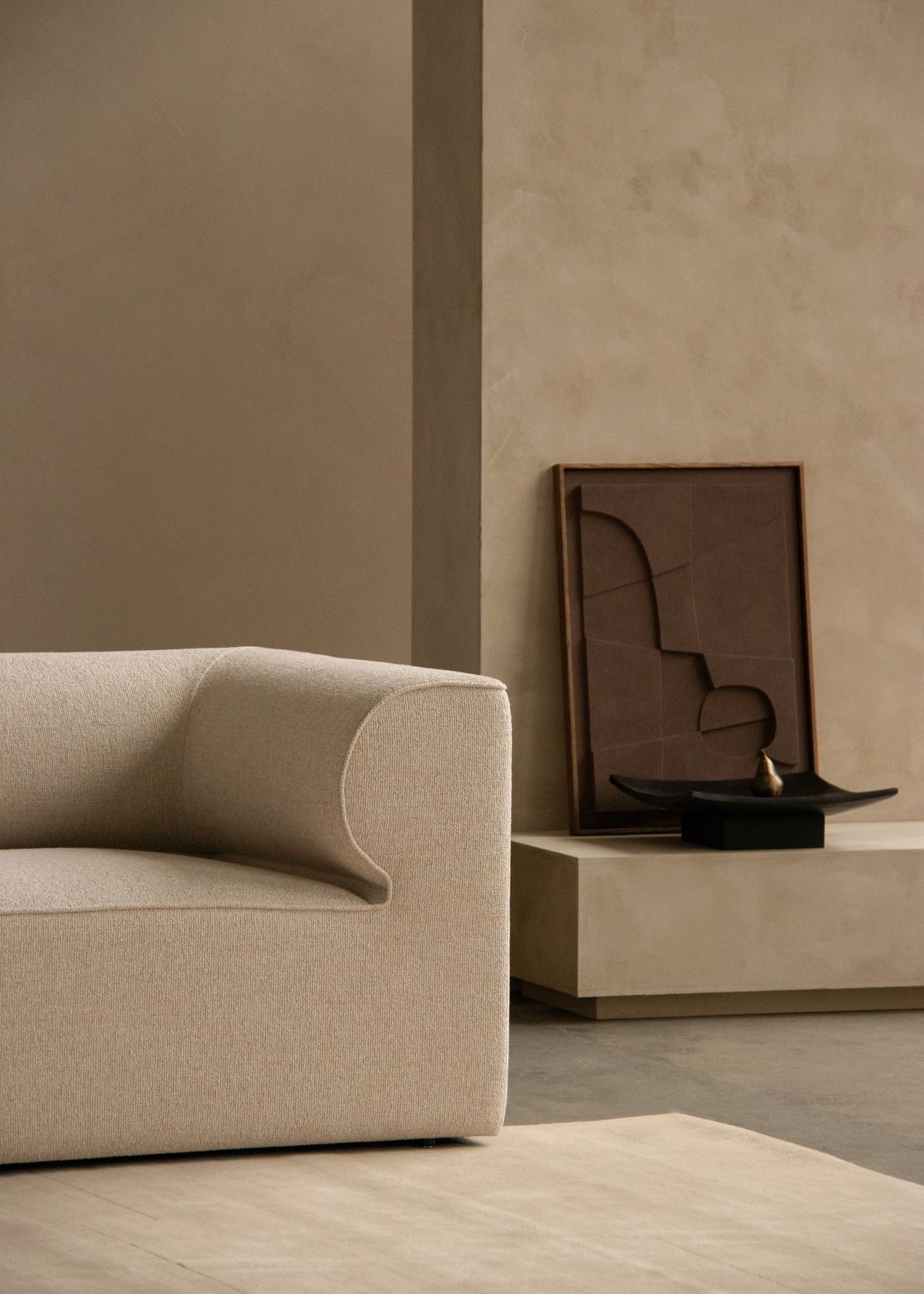 Detailaufnahme der Audo Copenhagen Relevé Platte, kombiniert mit abstrakter Kunst und minimalistischem Sofa.