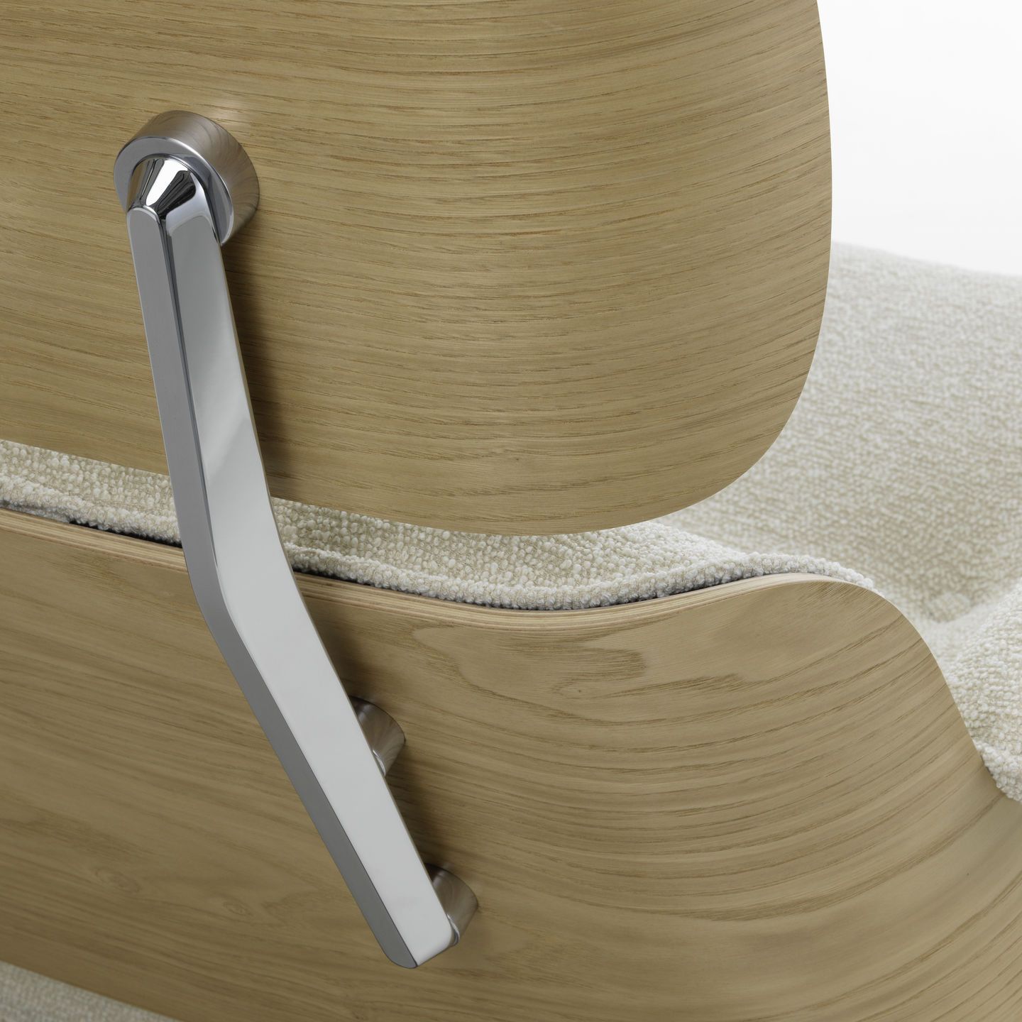 Detailaufnahme: Eames Lounge Chair Sessel von Vitra, helle Holzschale mit verchromtem Metallelement und beigem Stoffbezug.