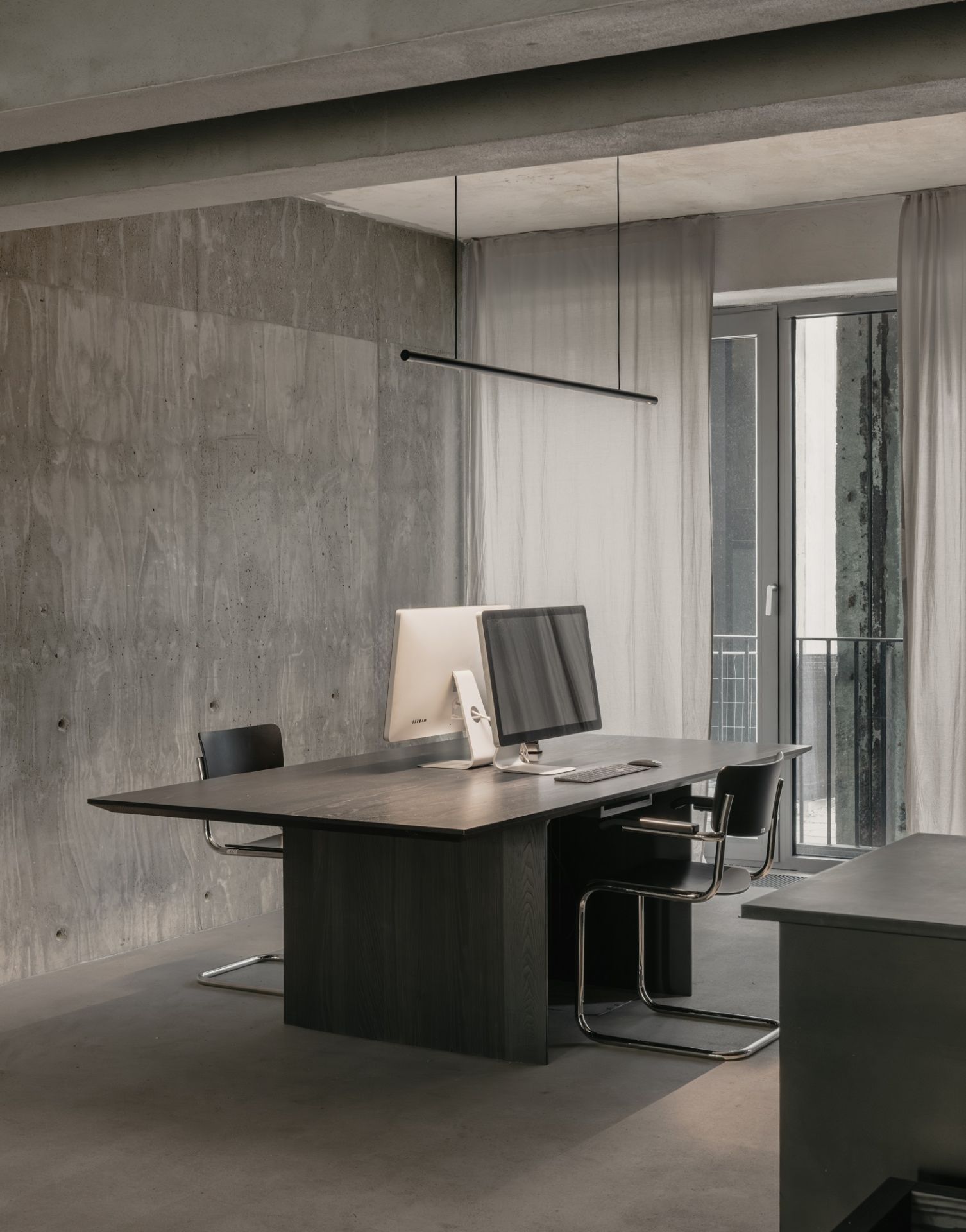 Moderne Büroeinrichtung mit w181 S2 Linier Pro Pendelleuchte von wästberg über dunklem Holztisch und Bürostühlen.