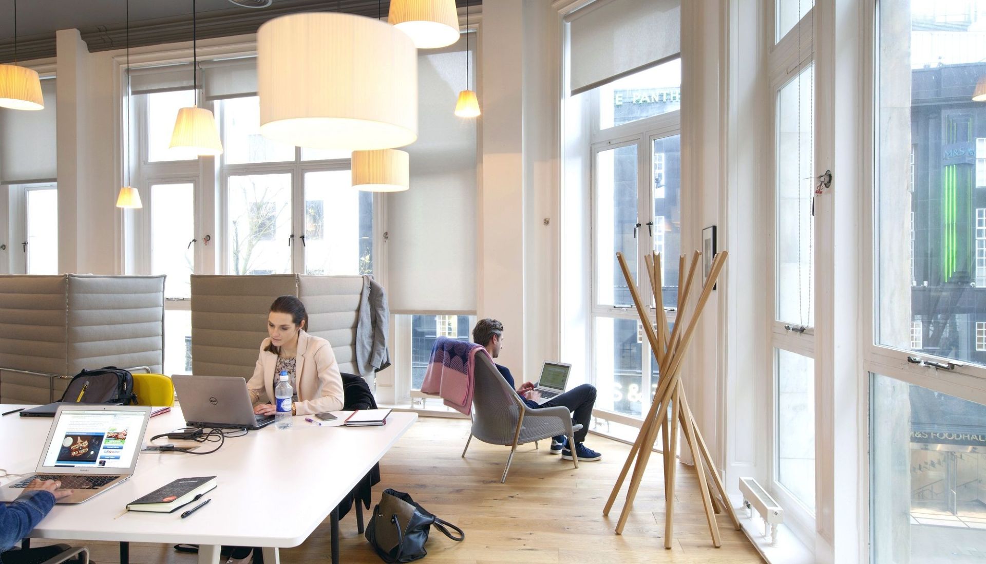 Heller Büroraum mit Mann im Vitra Slow Chair Sessel, der am Laptop arbeitet, Fokus auf ergonomisches Sitzen.