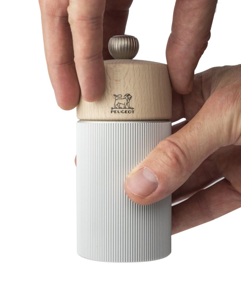 Hände bedienen eine Peugeot Line Salzmühle aus Aluminium und Holz, 12 cm, Nahaufnahme.