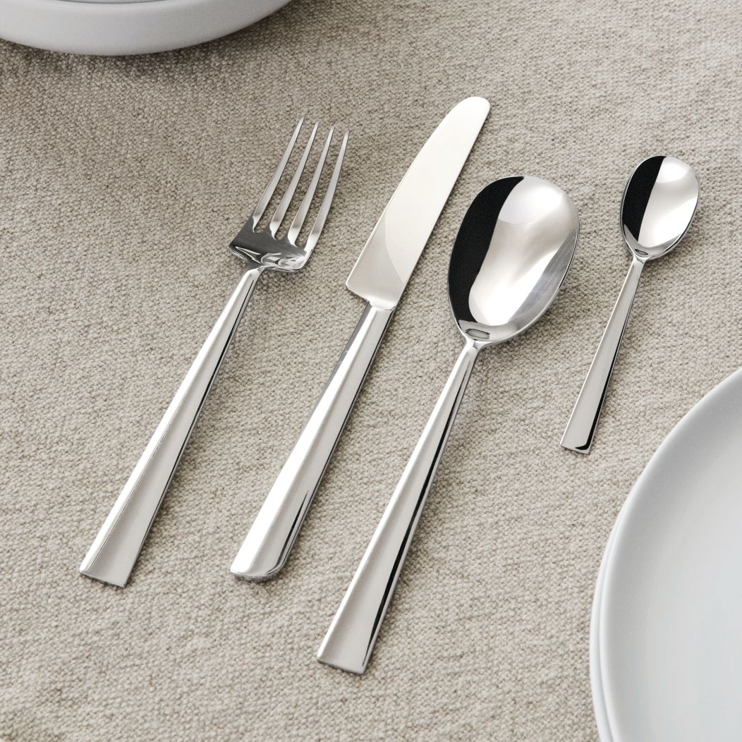 Nahaufnahme von Alessi Asta Besteck, Messer, Gabel, Esslöffel und Teelöffel auf Tischdecke.