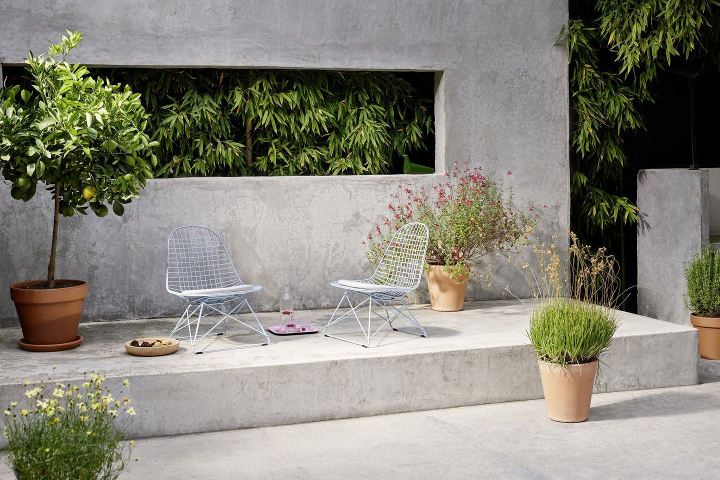 Zwei Vitra LKR-2 Wire Chairs mit Sitzbezug im Garten, minimalistisches Design, komfortable Sitzgelegenheit.