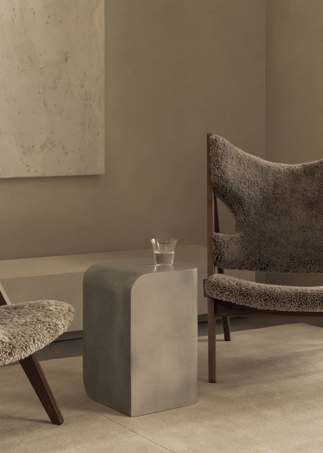 Audo Copenhagen Volume Side Table Beistelltisch aus Metall mit Wasserglas neben Sessel.