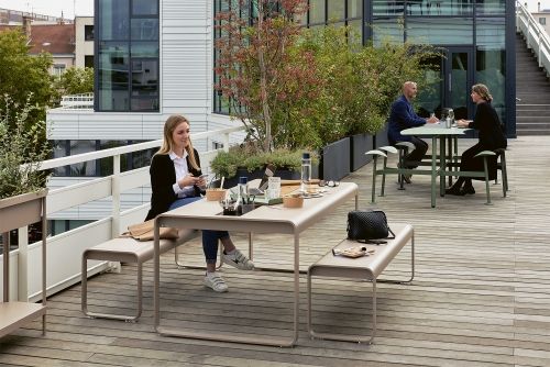 Bolder 3-Sitzer Gartentisch mit Sitzbänken von Fermob auf einer Dachterrasse mit Personen. Outdoor Möbel.