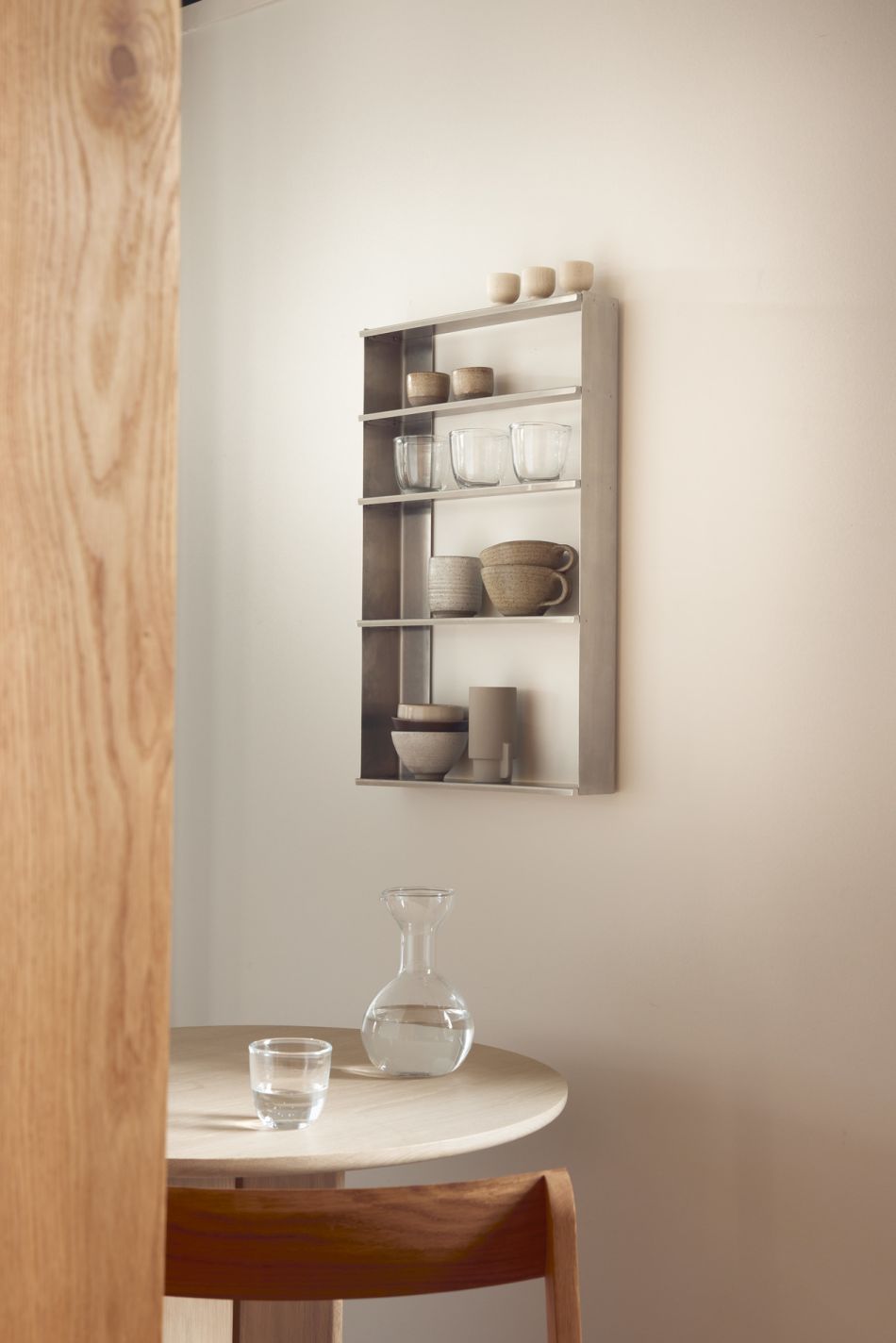 Taper Wandregal von Form & Refine, Metallregal mit Geschirr an einer beigen Wand.