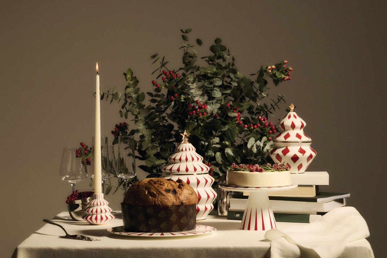 Festlicher Tisch mit Alessi Delight Etagere, Panettone, Kuchen, Kerze und Weihnachtsdekoration für eine stimmungsvolle Feier.