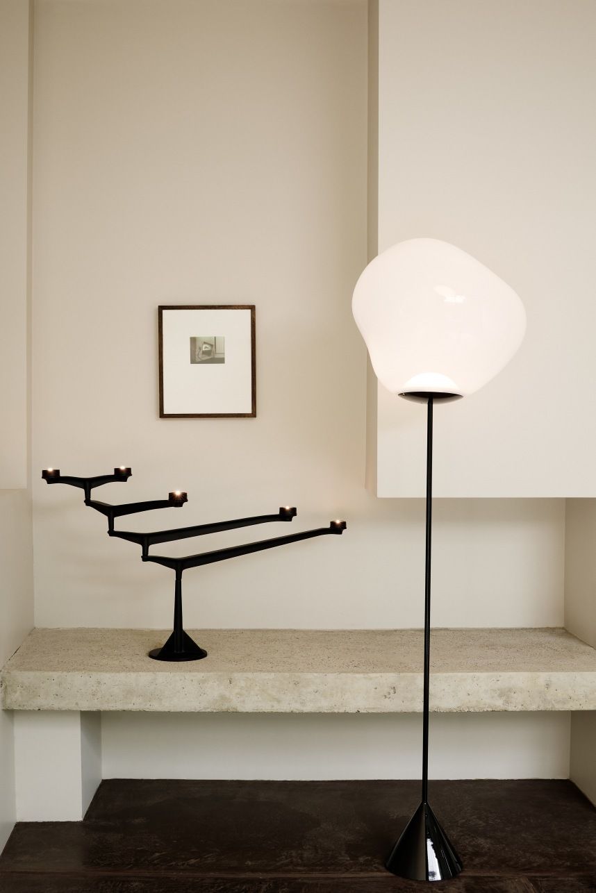 Schwarzer Spin Kerzenständer von Tom Dixon auf einem Betonsims, neben einer modernen Stehlampe in minimalistischem Interieur.