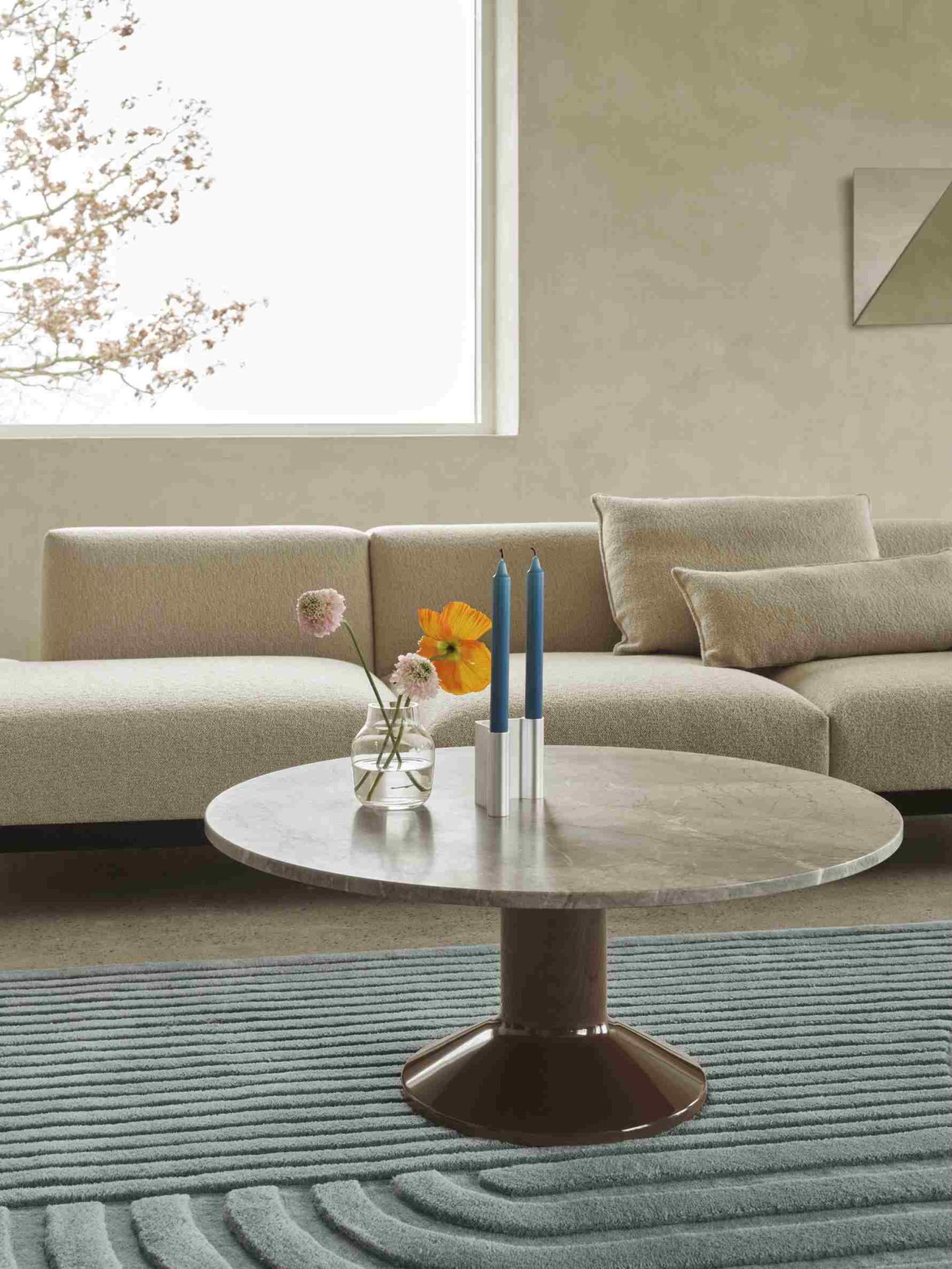 Muuto MIDST Coffee Table aus Marmor mit Blumen und Kerzen auf einem Teppich vor Sofa.