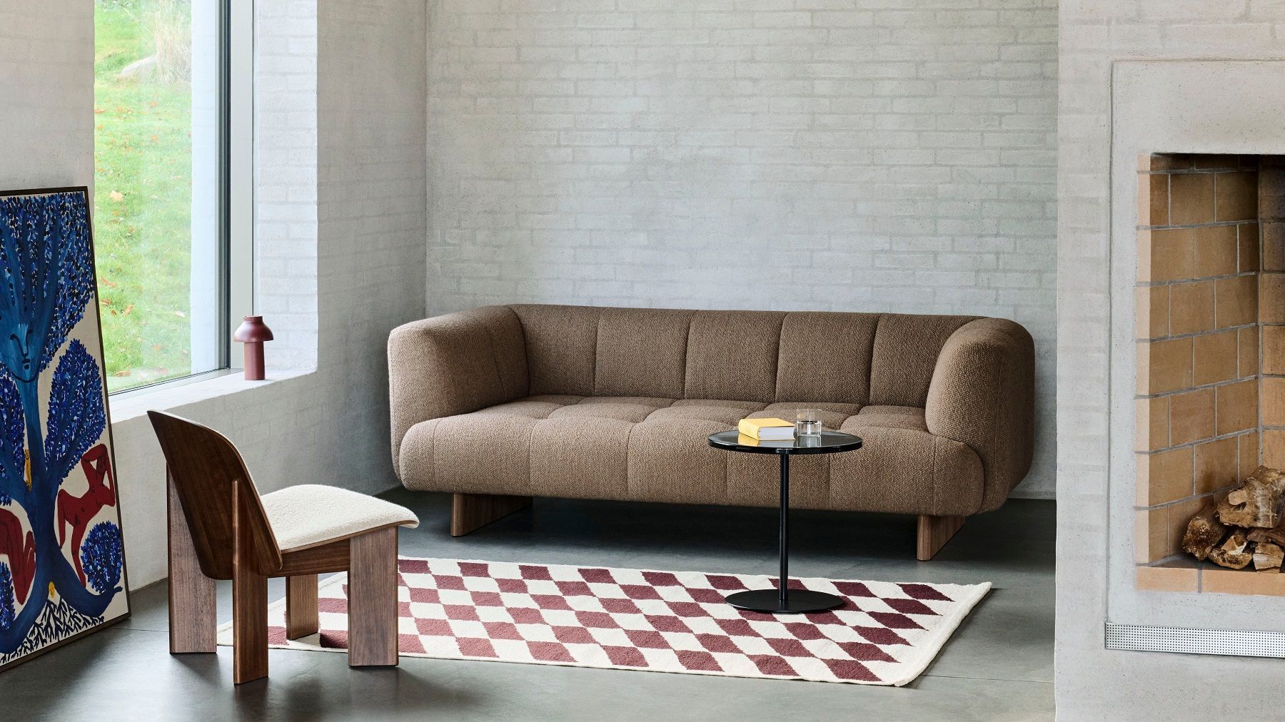 Wohnzimmer-Szene mit braunem Sofa, Hay Pyro Coffee Table, Holzstuhl und Schachbrett-Teppich für Indoor- und Outdoor-Bereiche.
