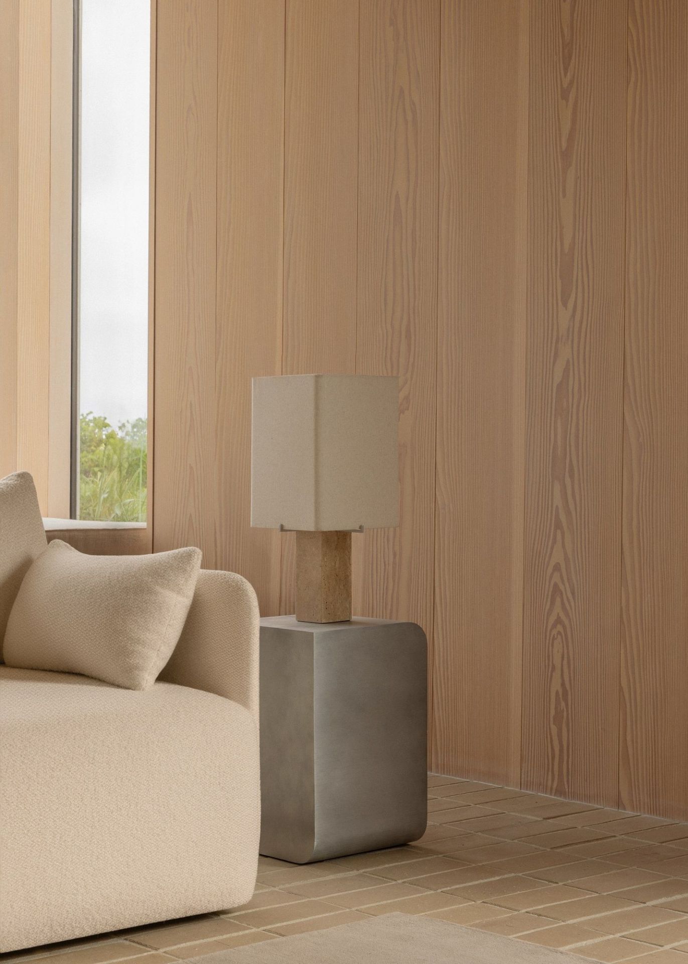 Audo Copenhagen Volume Side Table Beistelltisch aus grauem Beton neben einem beigen Sofa mit Kissen.