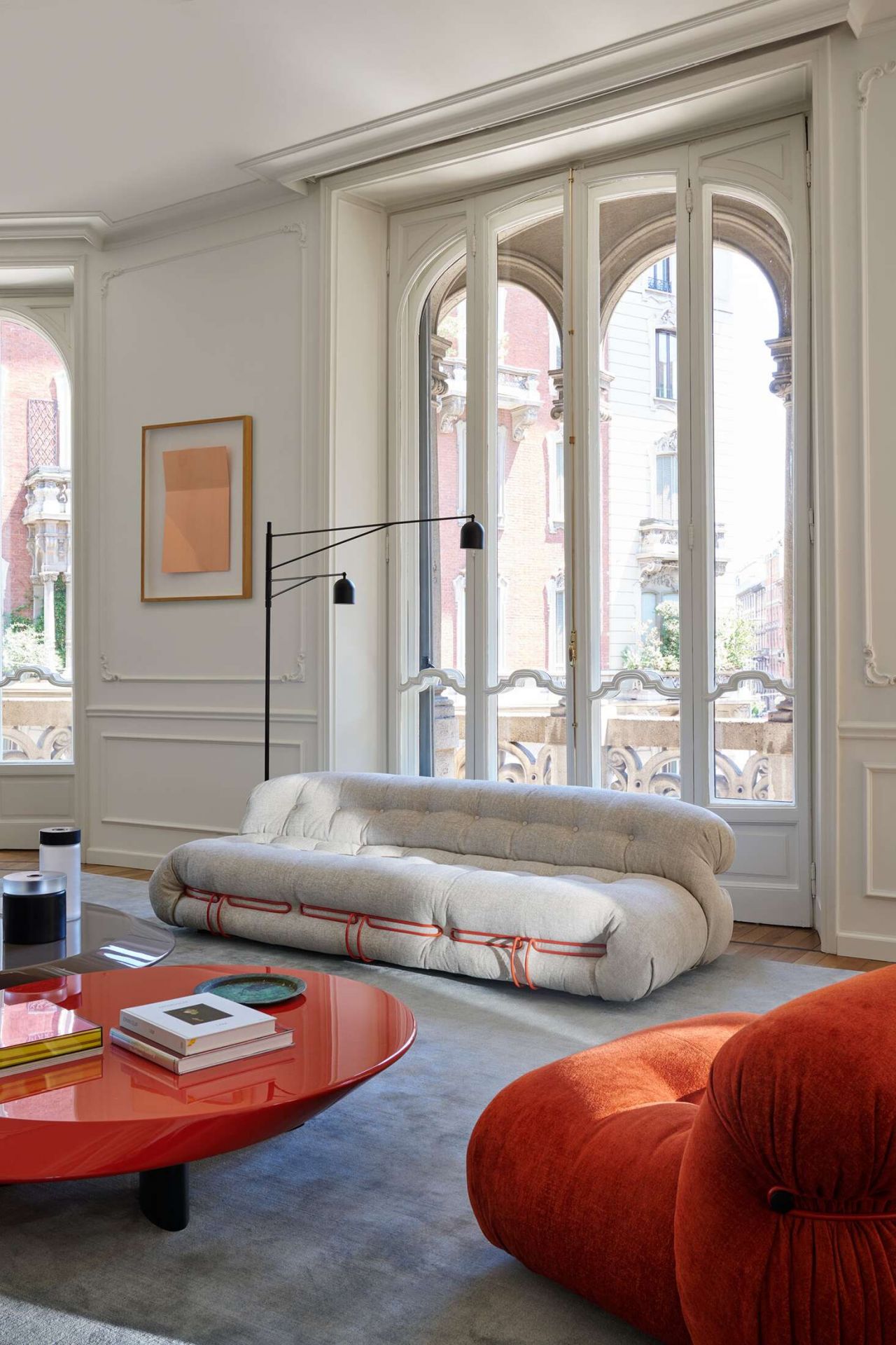 Helles Wohnzimmer mit Cassina Soriana Sofa in Beige und rotem Akzent, modernes Design.